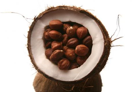 Hazelnuts in a split coconut on white background Stockfoto's