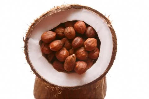 Hazelnuts in a split coconut on white background Foto stock