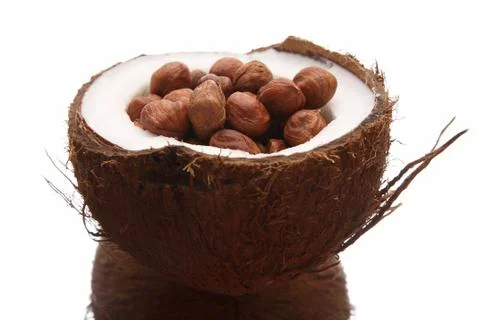 Hazelnuts in a split coconut on white background Foto stock