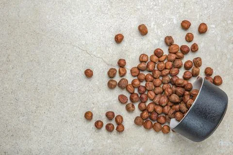 Hazelnuts on the table. A cup of hazelnuts flips over onto a marble top. Copy Stock Photos