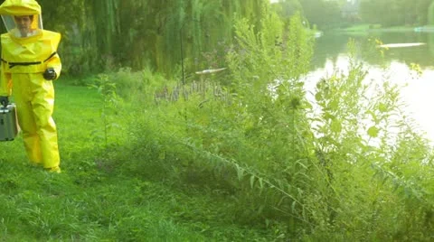 Hazmat guy walking by lake Stock Footage 11517635