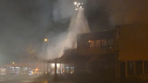 Hazy and smoky scene of disarray while ladder puts out remaining of fire Stock Footage 129986740