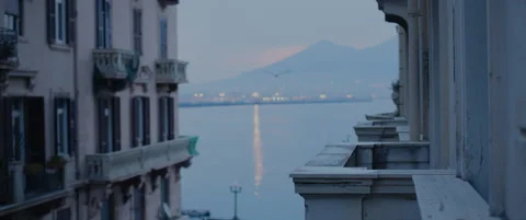 Hazy dawn between old buildings looking at Vesuvius over Naples bay Video stock 136397698