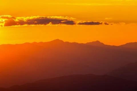 Hazy mountain range with dramatic sunset sky Stock Photos