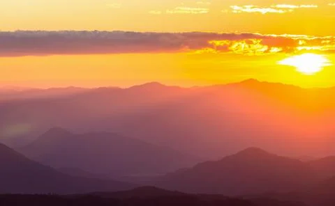 Hazy mountain range with dramatic sunset sky Stock Photos