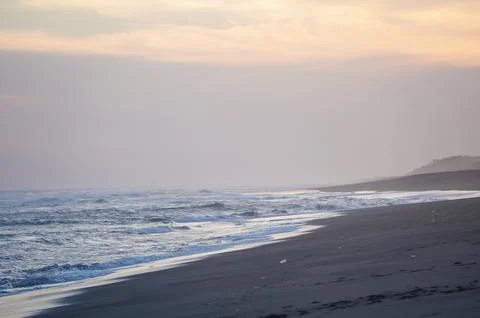 Hazy Sunset Beach With Rolling Waves Stock Photos