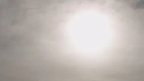 Hazy sunshine behind light grey slow moving clouds Stock Footage 129692449