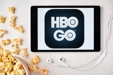 HBO GO logo on the screen of the tablet laying on the white table and sprinkled Stock Illustration