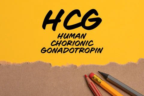 HCG human chorionic gonadotropin. Torn cardboard paper on yellow background Stock Photos