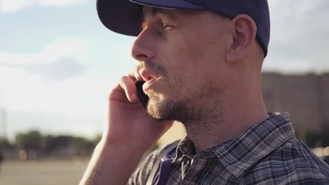 HD, 1920x1080. Slow motion. Man in shirt and cap talking on cell phone, nods his Stock Footage 78191254
