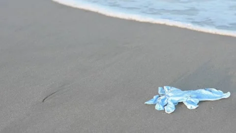 HD, Coronavirus polluting the environment. The waves wash up old used medical Stock Footage 132716874