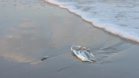HD, Coronavirus polluting the environment. The waves wash up old used medical Stock Footage 132717357