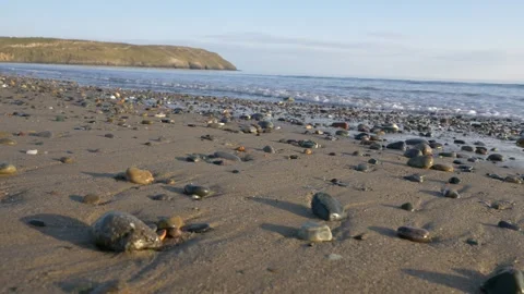 HD looking out to on the waves breaking on a sandy pebble shore, Wales 動画素材 185660935