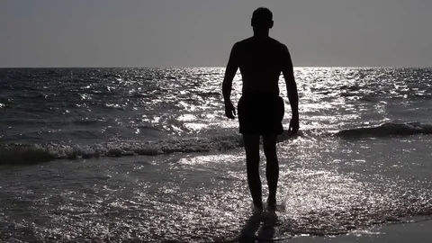 HD Slow Motion. Backlight of an athletic man walking along the beach Stock Footage 80093587