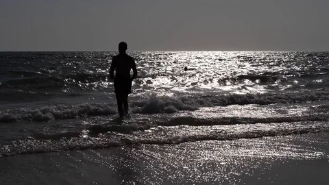 HD Slow Motion. Backlight of an athletic man walking along the beach Stock Footage 80093600