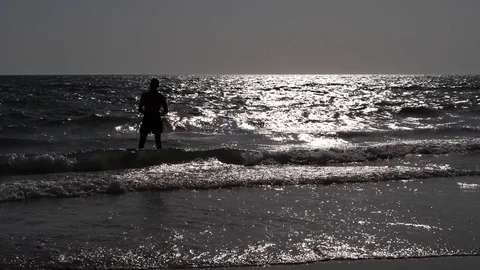 HD Slow Motion. Backlight of an athletic man walking along the beach Stock Footage 80093611