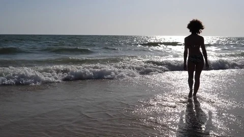 HD Slow Motion. Backlight of a Caucasian woman walking towards the sea Stock Footage 80093635
