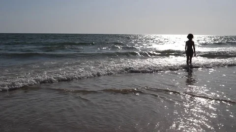 HD Slow Motion. Backlight of a Caucasian woman walking towards the sea Stock Footage 80093639