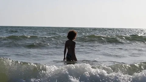 HD Slow Motion. Backlight of a caucasian woman playing with the waves of the sea Stock Footage 80093645