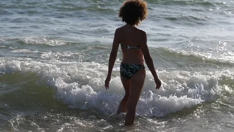 HD Slow Motion. Backlight of a caucasian woman playing with the waves of the sea Stock Footage 80093647