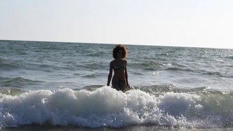 HD Slow Motion. Backlight of a caucasian woman playing with the waves of the sea Stock Footage 80093656