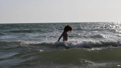HD Slow Motion. Backlight of a caucasian woman playing with the waves of the sea Stock Footage 80093666