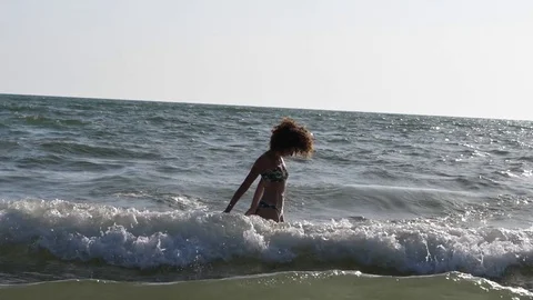 HD Slow Motion. Backlight of a caucasian woman playing with the waves of the sea Stock Footage 80093670