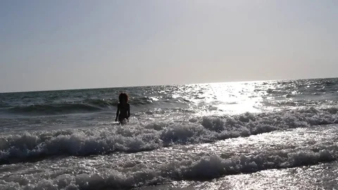 HD Slow Motion. Backlight of a caucasian woman playing with the waves of the sea Stock Footage 80093675