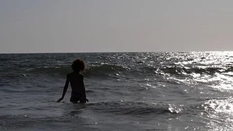 HD Slow Motion. Backlight of a caucasian woman playing with the waves of the sea Stock Footage 80093679