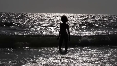 HD Slow Motion. backlight of a young woman standing at the edge of the sea Stock Footage 80093792