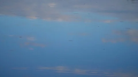 HD slow motion, raindrops beginning to fall on the blue calm surface of a lake Stock Footage 106932146