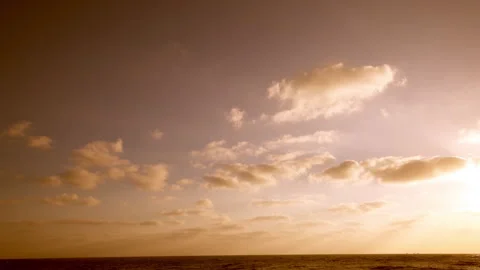 HD slow-motion shot of golden clouds drifting across the sky above a calm ocean. Stock Footage 341110064