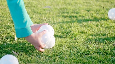 HD. Slow Motion. White Plastic Baseballs. Girl picks up from grass Wiffle Balls. Video stock 87758997