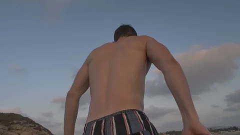 HD slow motion young man jumping from high rocky ledge Into the ocean. Stock Footage 116060604