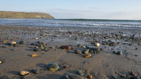 HD waves breaking on a sandy pebble shore along the Welsh coast Видео 185661017