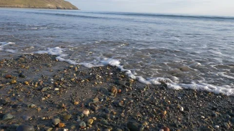 HD waves breaking on a sandy pebble shore along the Welsh coast Stock Footage 185661402