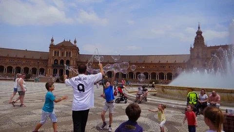HD.Slow motion. Children playing with soap bubbles in Plaza de España in Seville Stock Footage