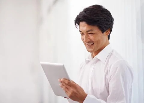He always has access to important data. a handsome asian businessman using his Foto stock