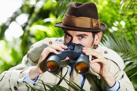 He doesnt miss a thing. Private investigator using binoculars to spy on someone Stock Photos