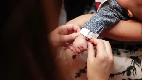 He godmother puts the bracelet on the boy's hand after the baptism Stock Footage 132071353