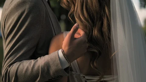 He groom strokes the bride's back. Bride and groom embracing outdoors.  Stock Footage 128580252