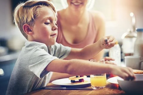He has such a healthy appetite. a little boy having breakfast at home. Stock Photos