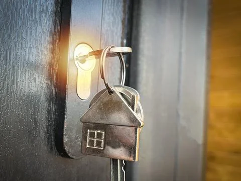 He key in the lock of the front door and a keychain in the form of a house .. Stock Photos