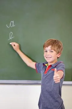 He knows the answer. A young boy writing on the blackboard at school. Stock Photos