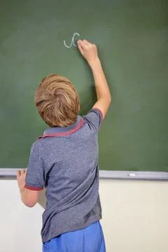 He knows the answer. A young boy writing on the blackboard at school. Stock Photos