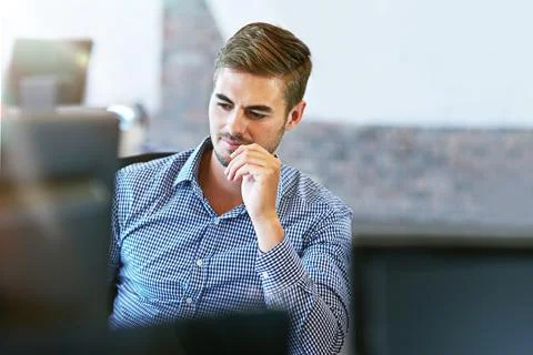 He knows what hes doing. a young businessman using a computer in an office. Stockfoto's