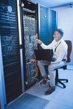 He knows where every wire goes. a mature man using a laptop while working in a Stock Photos