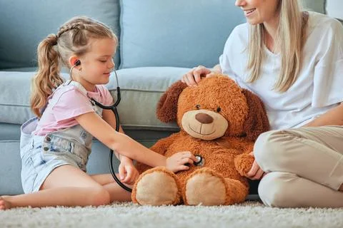 He needs a checkup. a little girl and her mother playing doctor with a teddybear Stock Photos