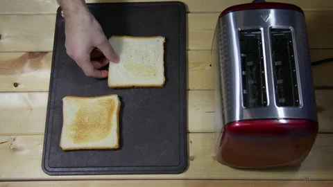 He pulls out the toasted bread from the toaster and puts it on the table Stock Footage 122123255