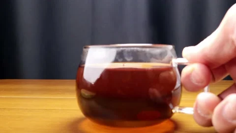He puts the steaming hot tea in a glass mug on the table 스톡 동영상 184604108